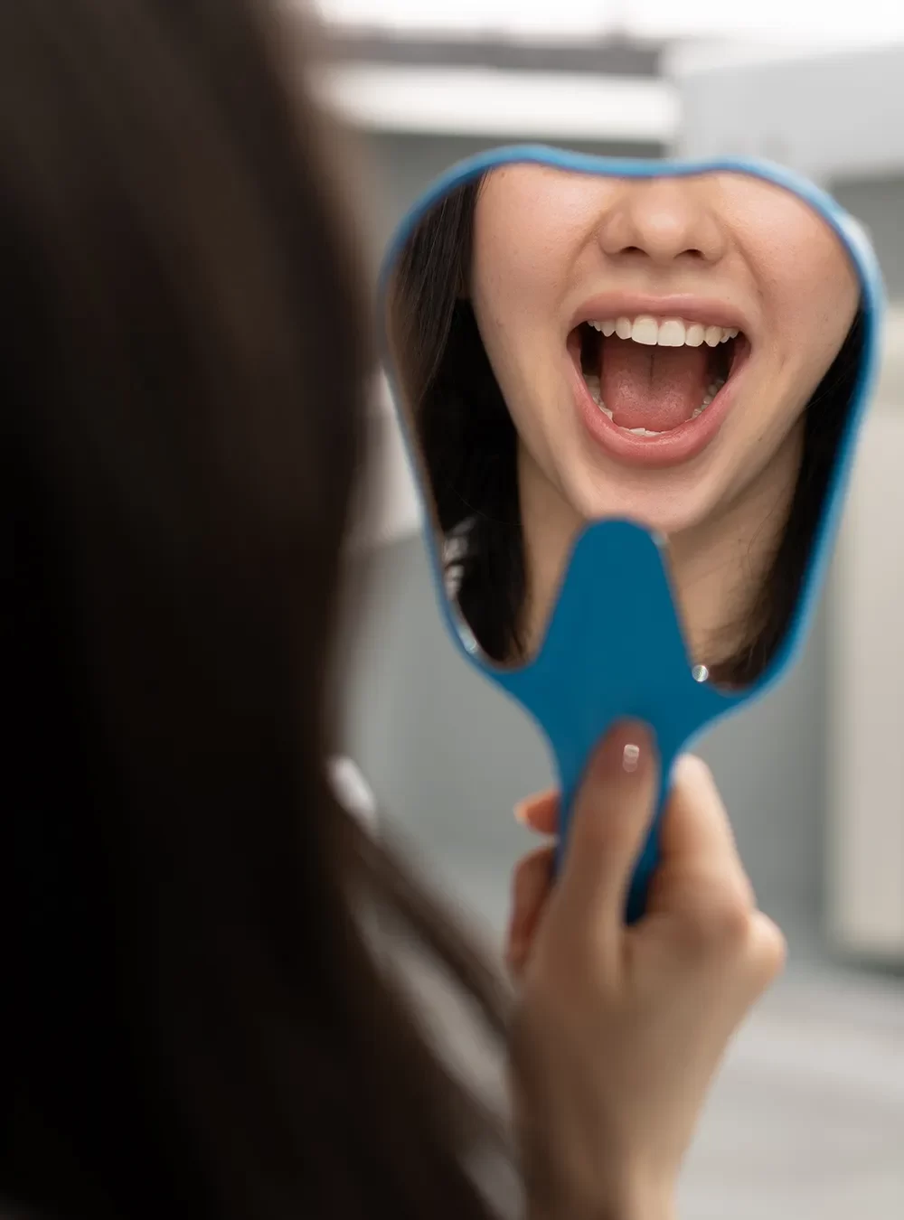 Satisfied patient at Onyx Dental Clinic looking in the mirror at their teeth.