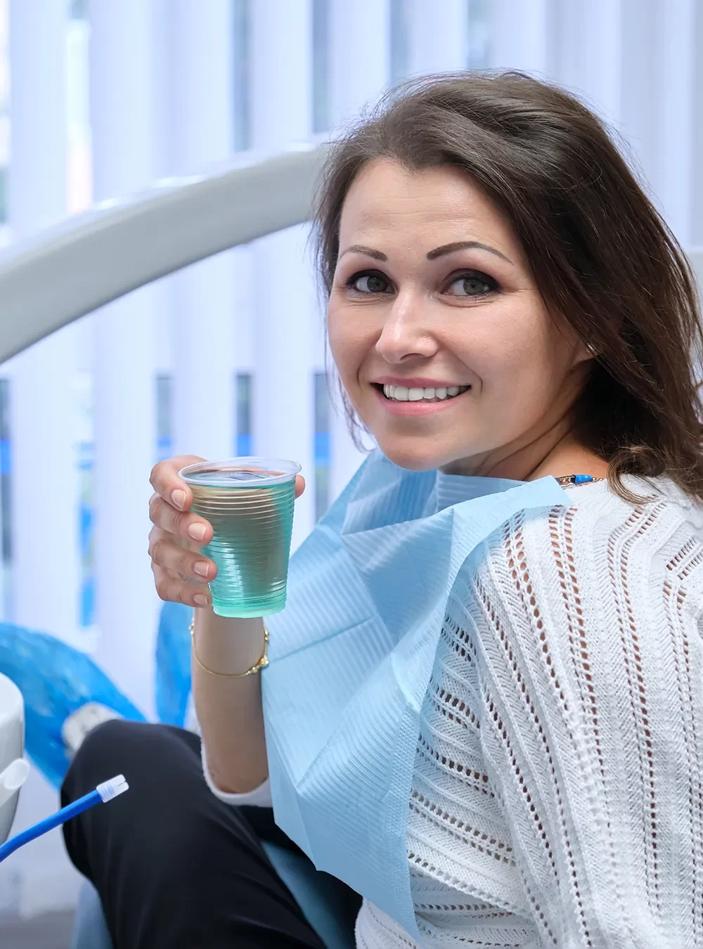 Smiling patient holding a glass of water while comfortably waiting for their dental treatment at Onyx Dentistry, enjoying a relaxing and stress-free experience.