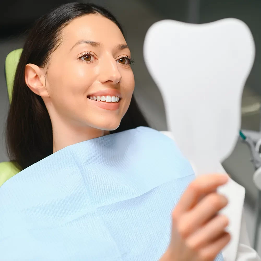 Happy patient admiring their teeth in the mirror after dental care at Onyx.