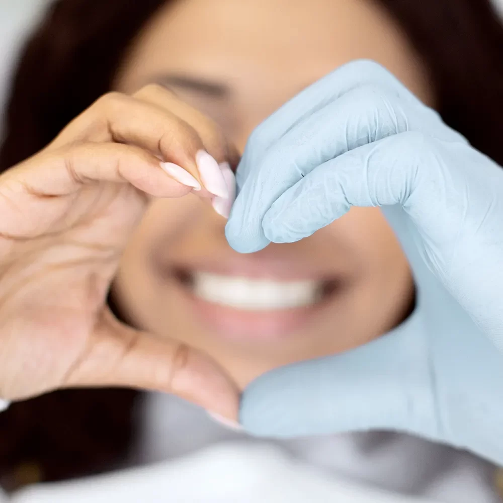 Smiling patient forming a heart shape with their hands, symbolizing love for their healthy, beautiful smile after dental care at Onyx Dentistry.